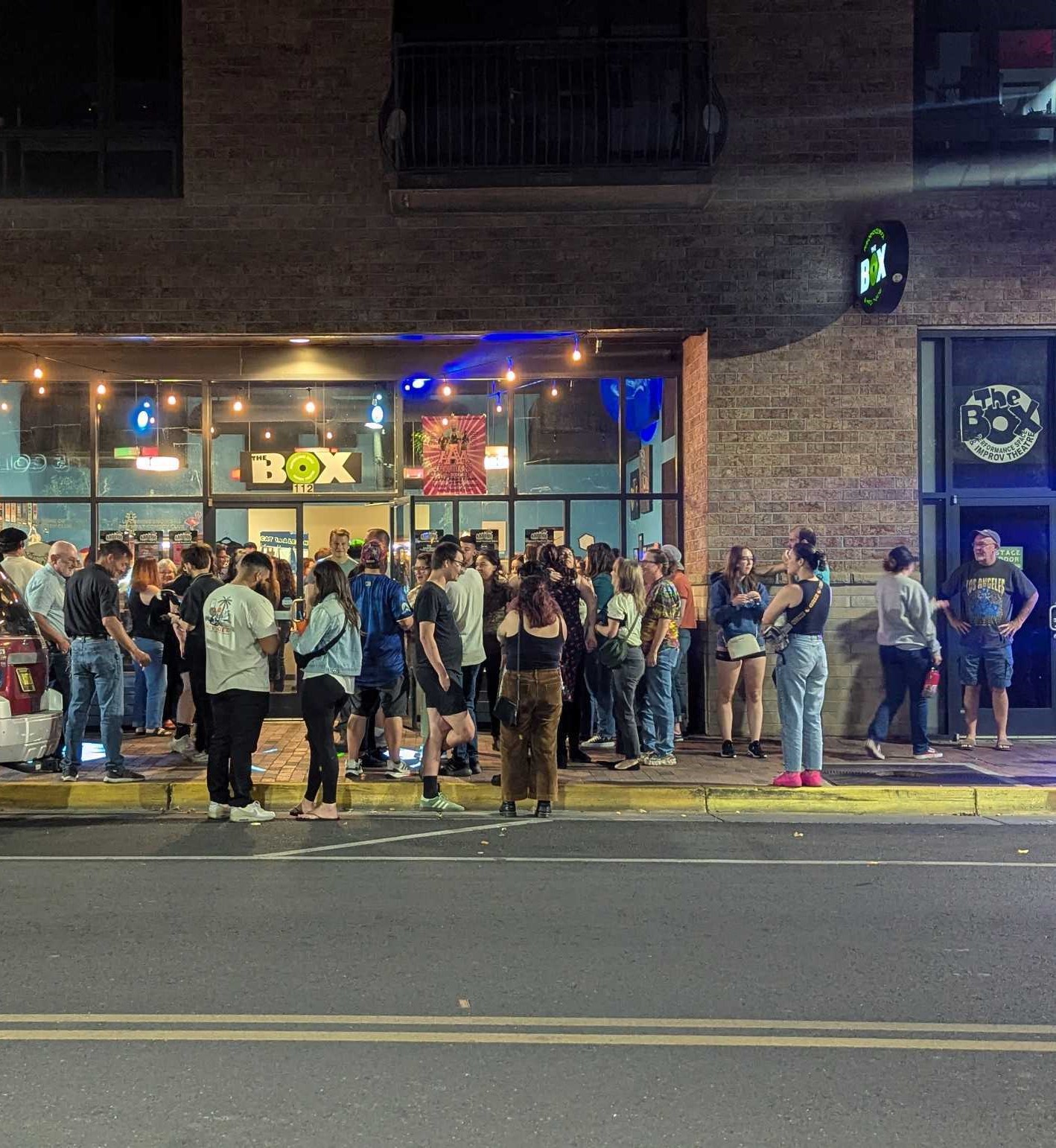 A crowd gathers on the sidewalk waiting to enter the venue for Arts Hub's Funny Fiesta in Albuquerque, New Mexico.